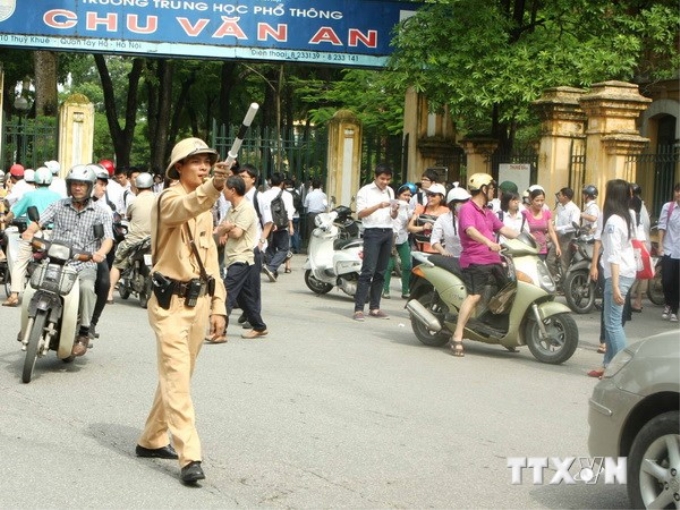 Cảnh sát giao thông phân luồng, điều tiết giao thông tại khu vực cổng Trường THPT Chu Văn An (Hà Nội) sau giờ thi tốt nghiệp THPT. (Ảnh: Minh Quyết/TTXVN)